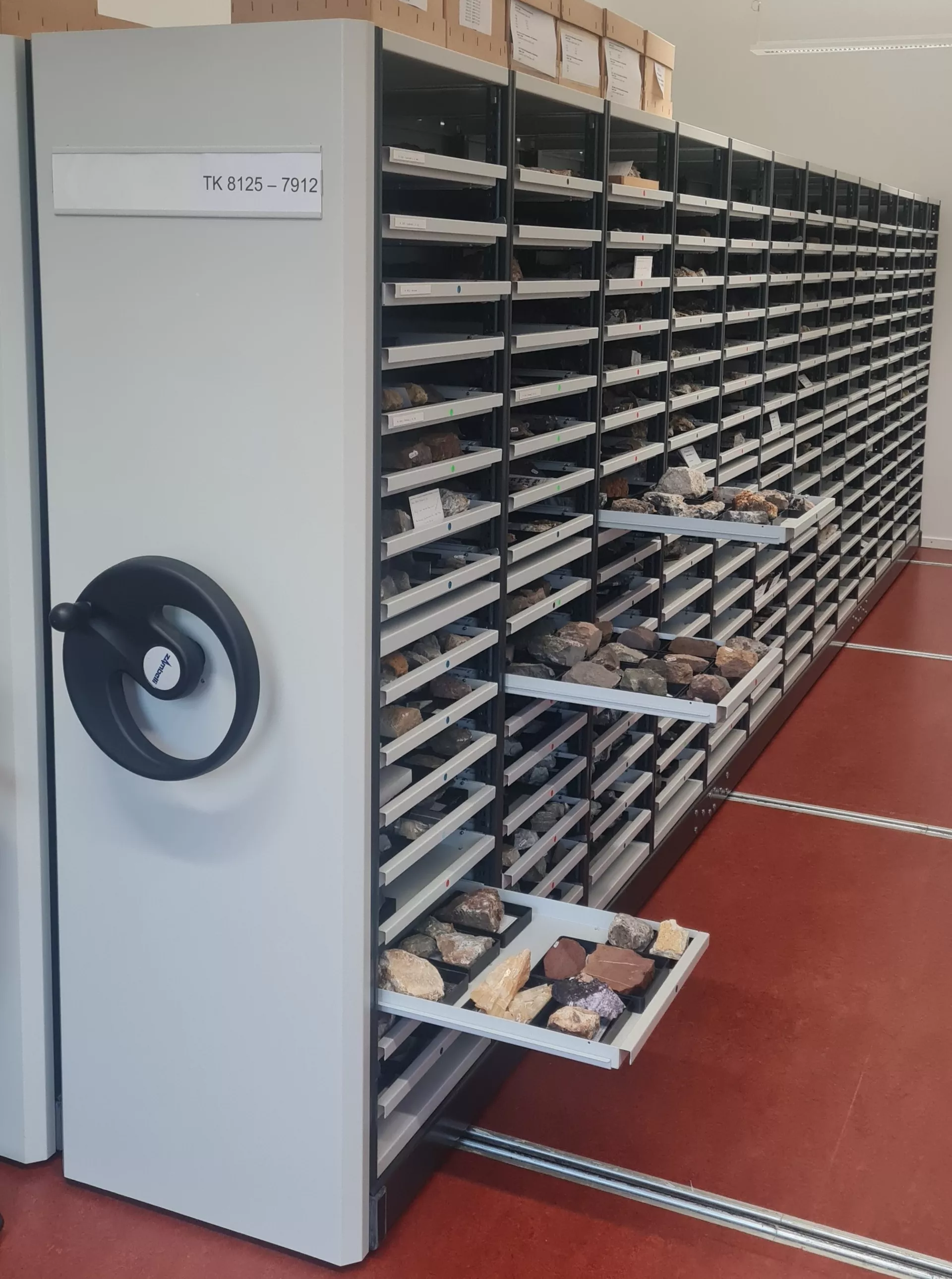 Graue Rollschränke der Mineralogisch-Petrographischen Sammlung mit teilweise geöffneten Schubladen, in denen Gesteinshandstücke liegen.