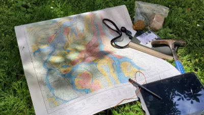 Geologische Karte die in Bearbeitung ist, Gesteinsproben, Feldbuch, Geologenhammer, Tablet