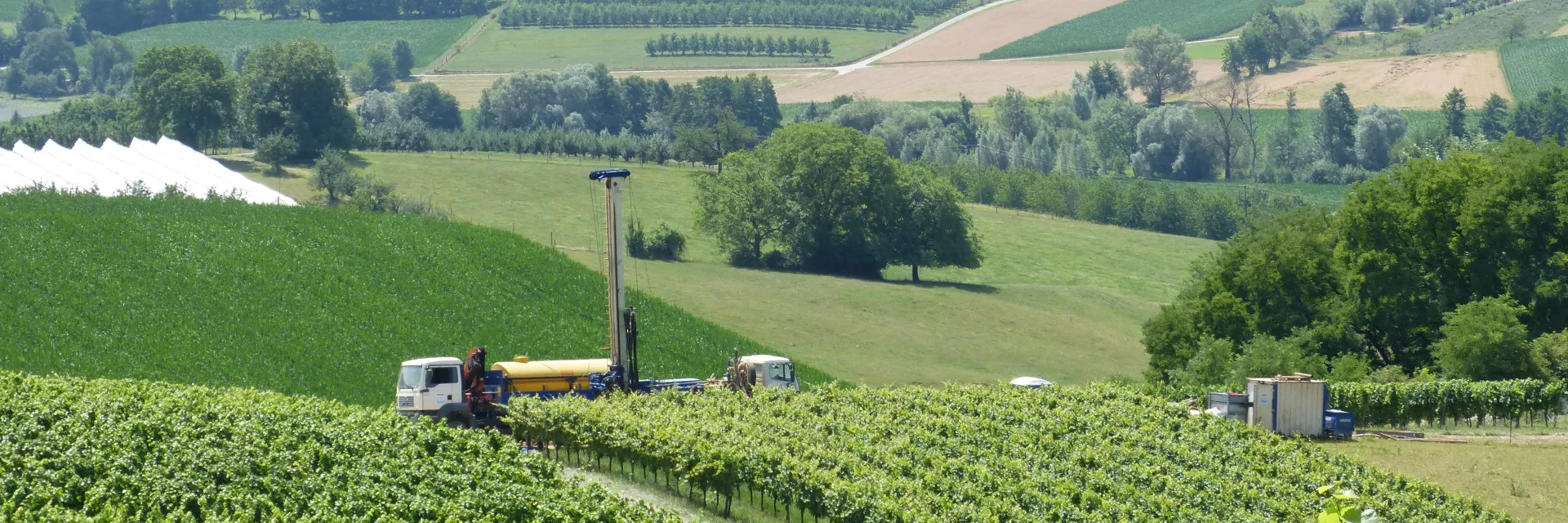 Ein LKW steht auf einem Weg in den Weinbergen und transportiert eine Bohranlage.