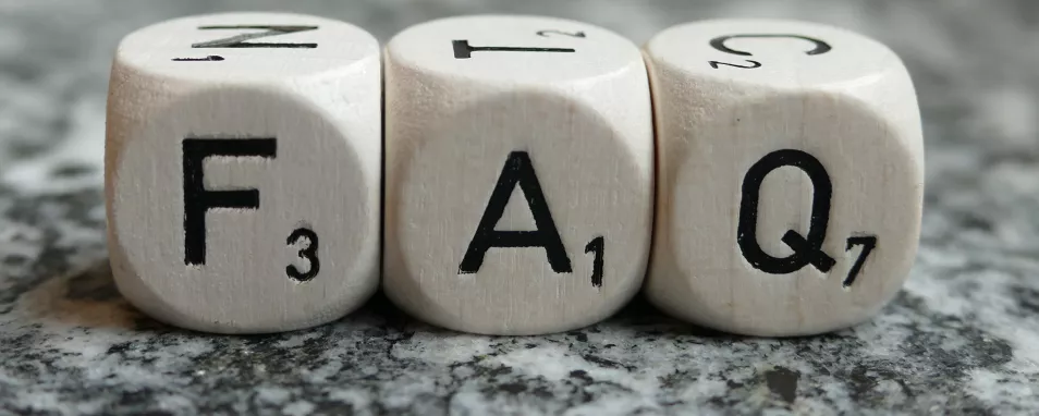Auf einem polierten Stein liegen nebeneinander drei weiße Würfel mit den Buchstaben "F", "A" und "Q"